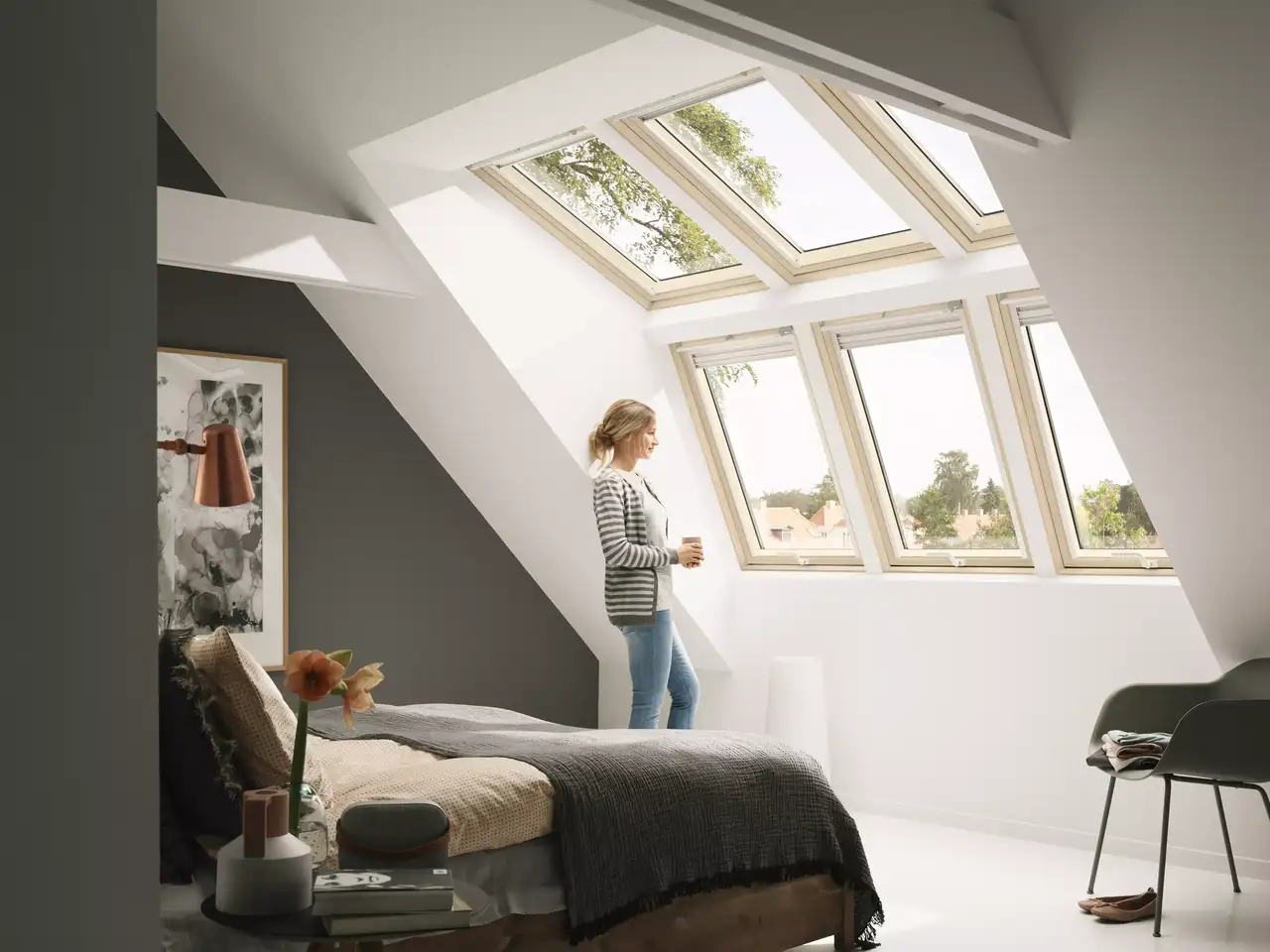 Schlafzimmer im Dachboden mit natürlichem Licht von VELUX Dachflächenfenstern und minimalistischer Dekoration.