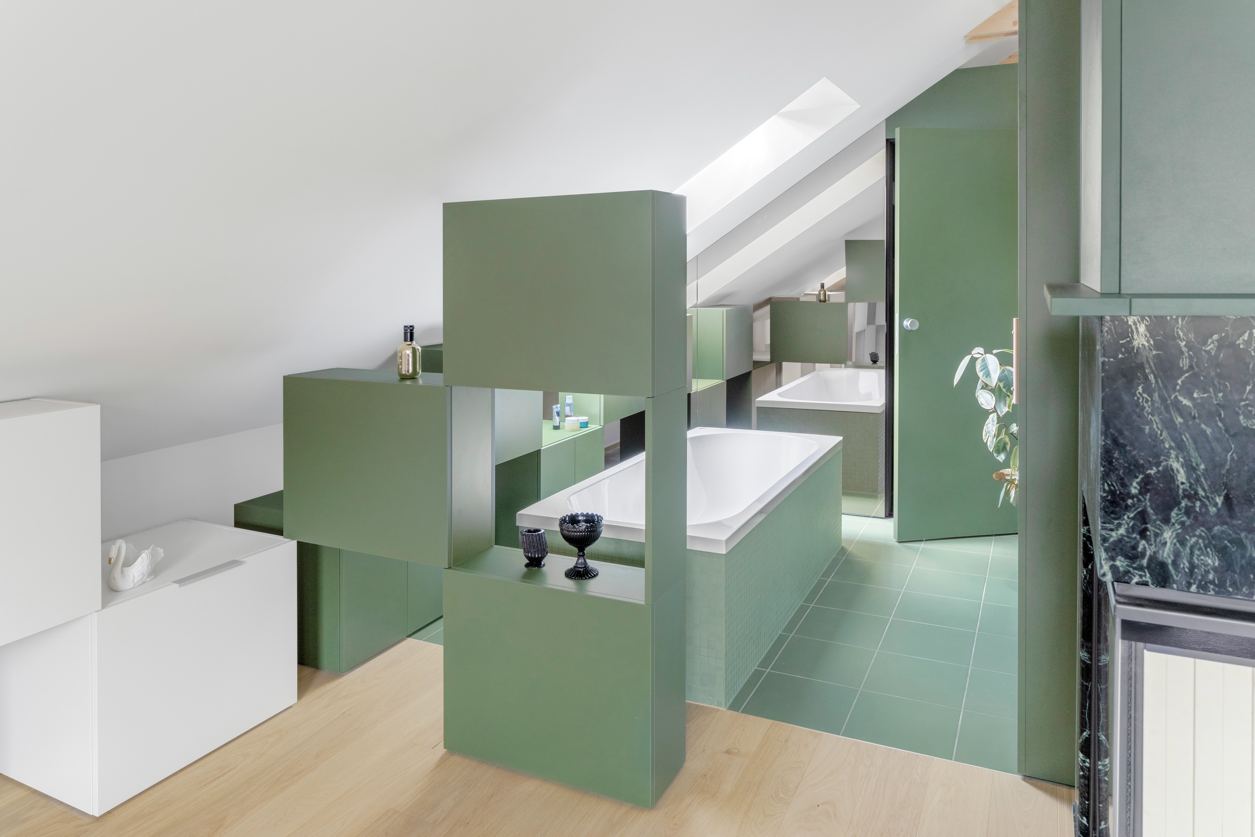 Kúpeľňa v podkroví so šikmým stropom, strešným oknom VELUX a modernými zelenými skrinkami