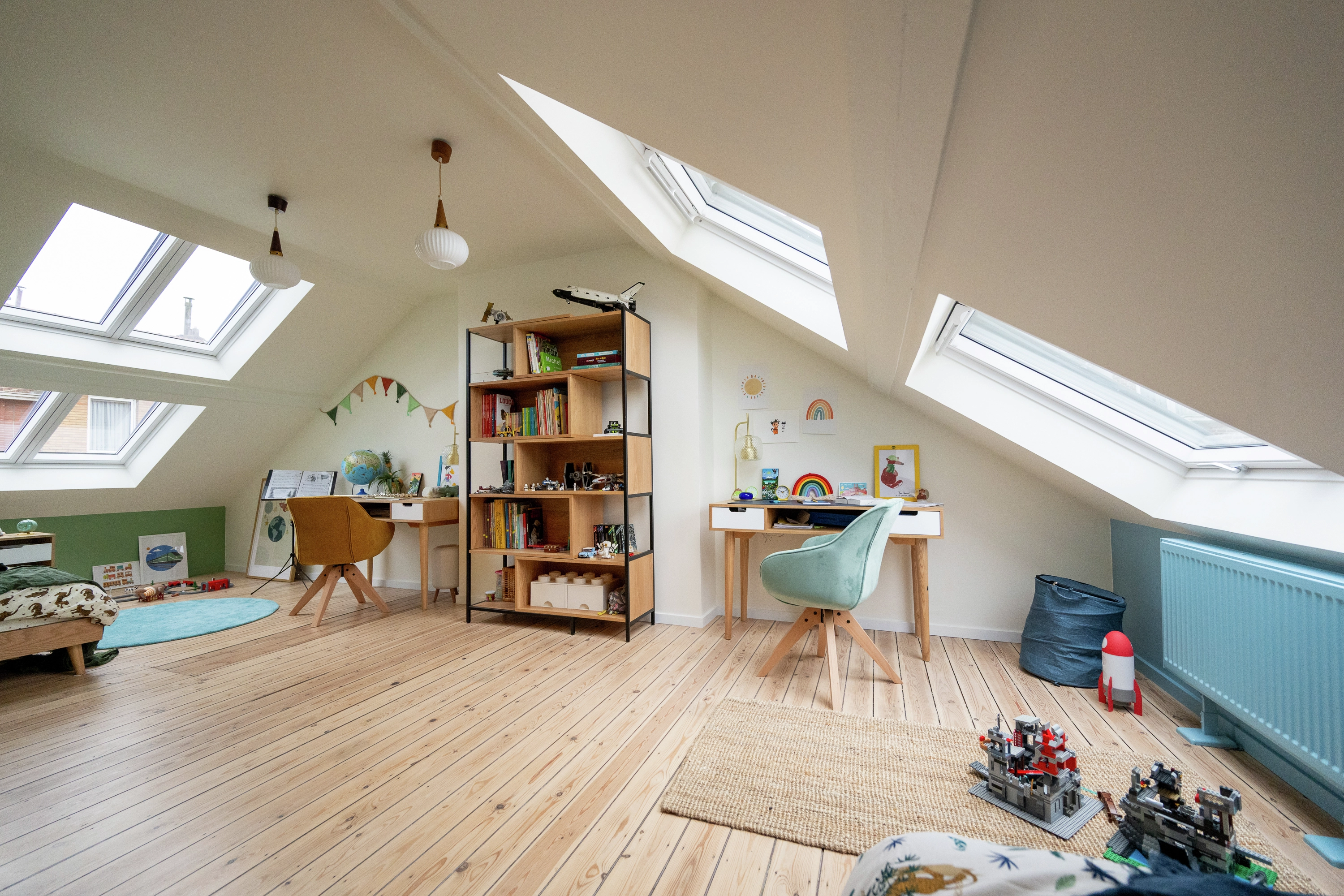 Chambre d’enfant rénovée sous combles et deux fenêtres de toit laissant entrer la lumière naturelle.