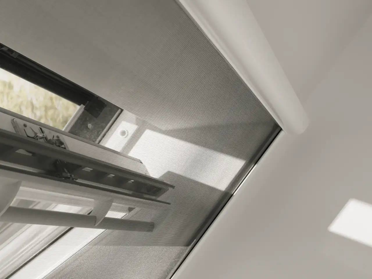 Detail van een VELUX dakvenster met de bovenste cassette van het muggengaas in het kozijn geïnstalleerd