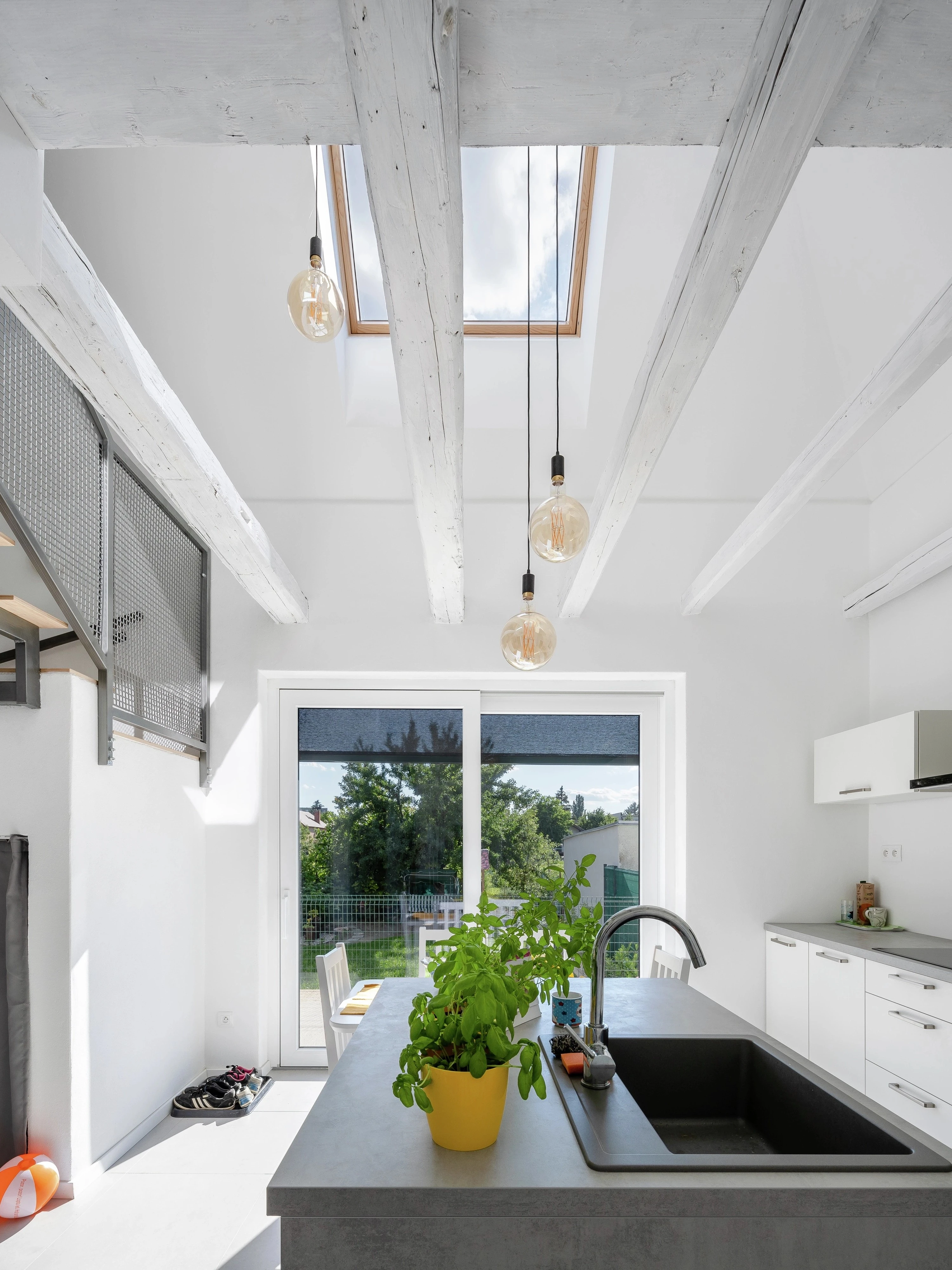 Világos, nyitott konyhai tér látszó fa gerendákkal, konyhaszigettel és VELUX tetőablakkal, amely felülről természetes fénnyel világítja meg a helyiséget. 