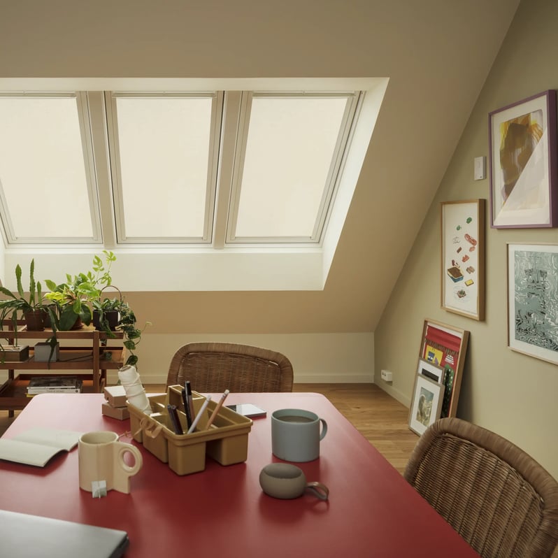 Attic workspace with sloped ceiling, VELUX roof window, and vibrant decor.
