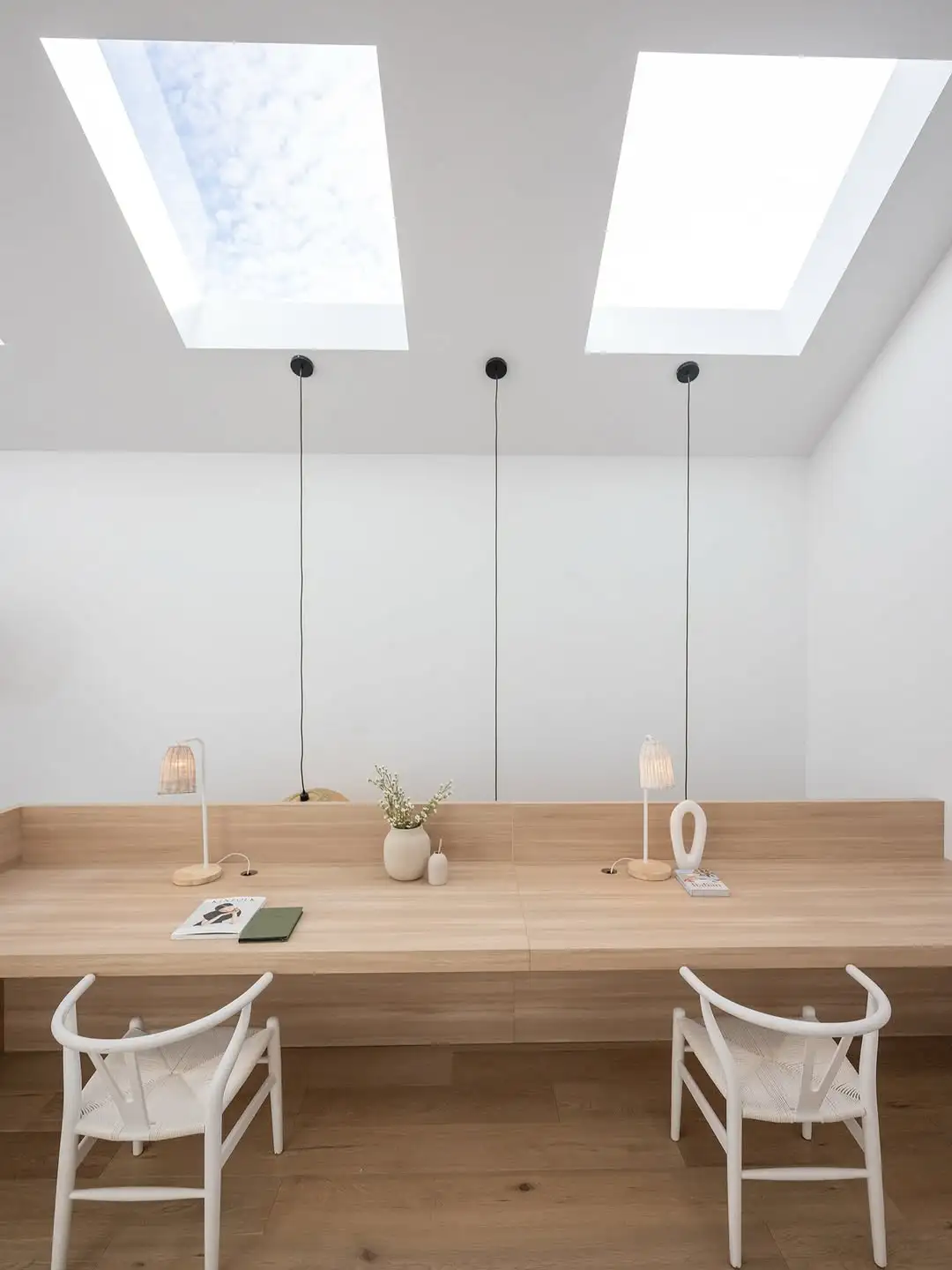 Minimalist home office with wooden desk and skylights.