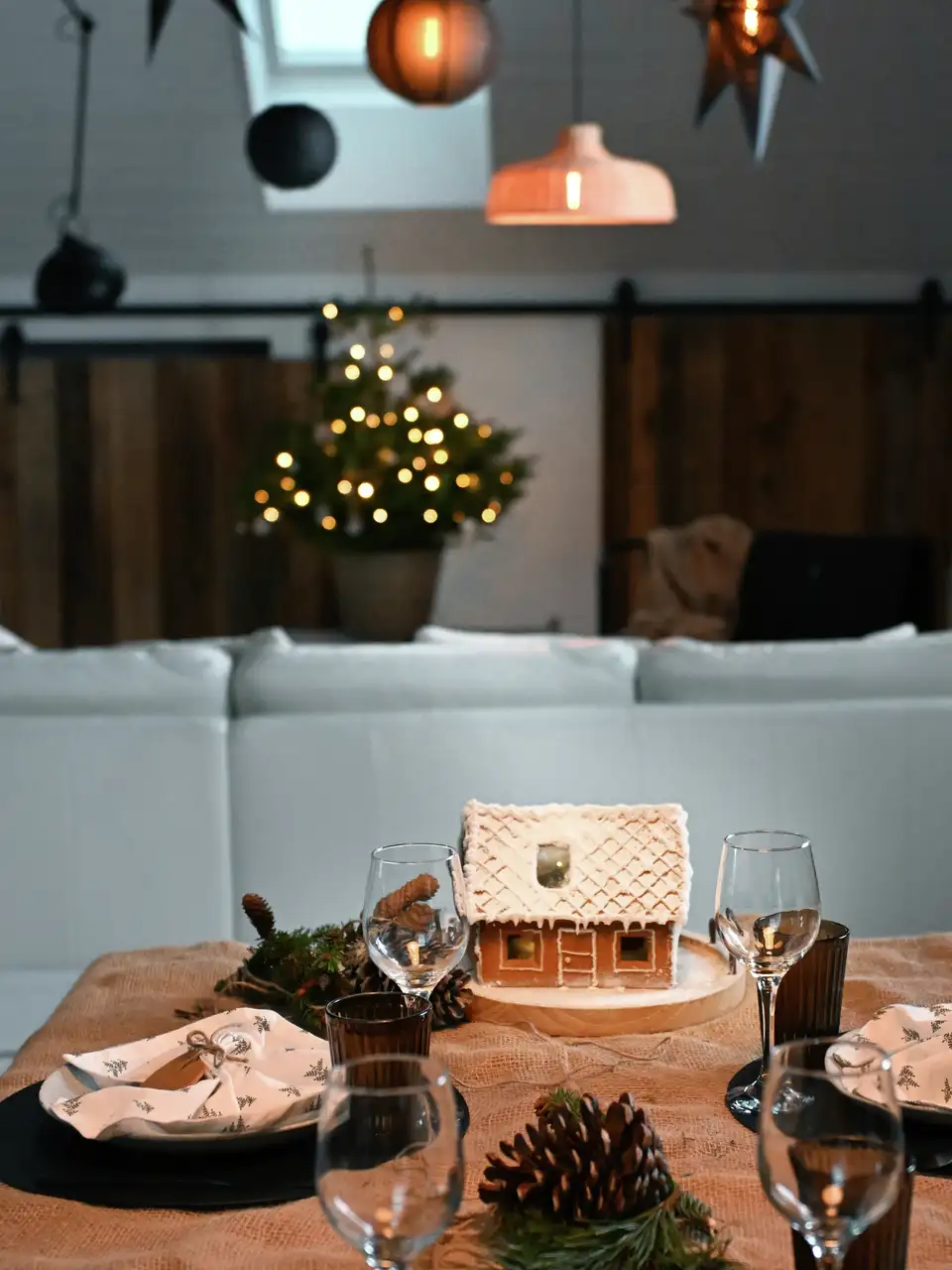 Tavola natalizia con casetta di pan di zenzero, pigne e rami di pino, illuminata da una  finestra per tetti VELUX.