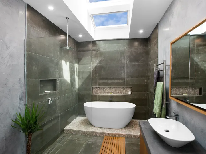 Modern bathroom with skylight and freestanding bathtub.