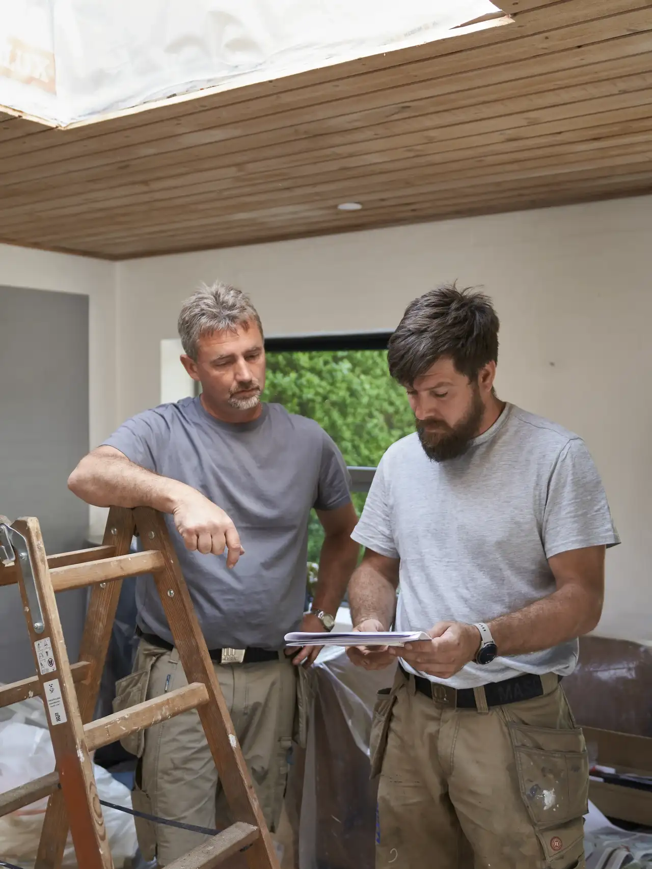 Zwei Handwerker besprechen die Dachausbau-Genehmigung | VELUX Magazin