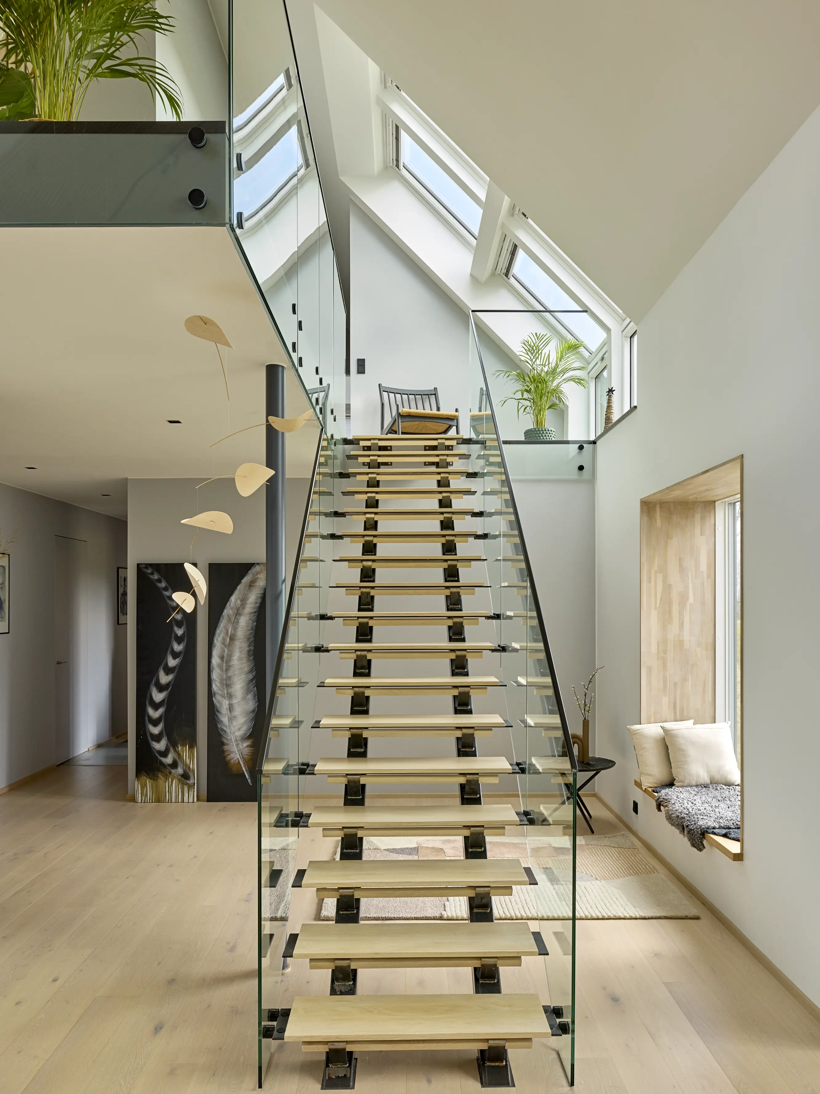 Loft con  scala moderna con ringhiere in vetro e finestre per tetti VELUX nella parte superiore.