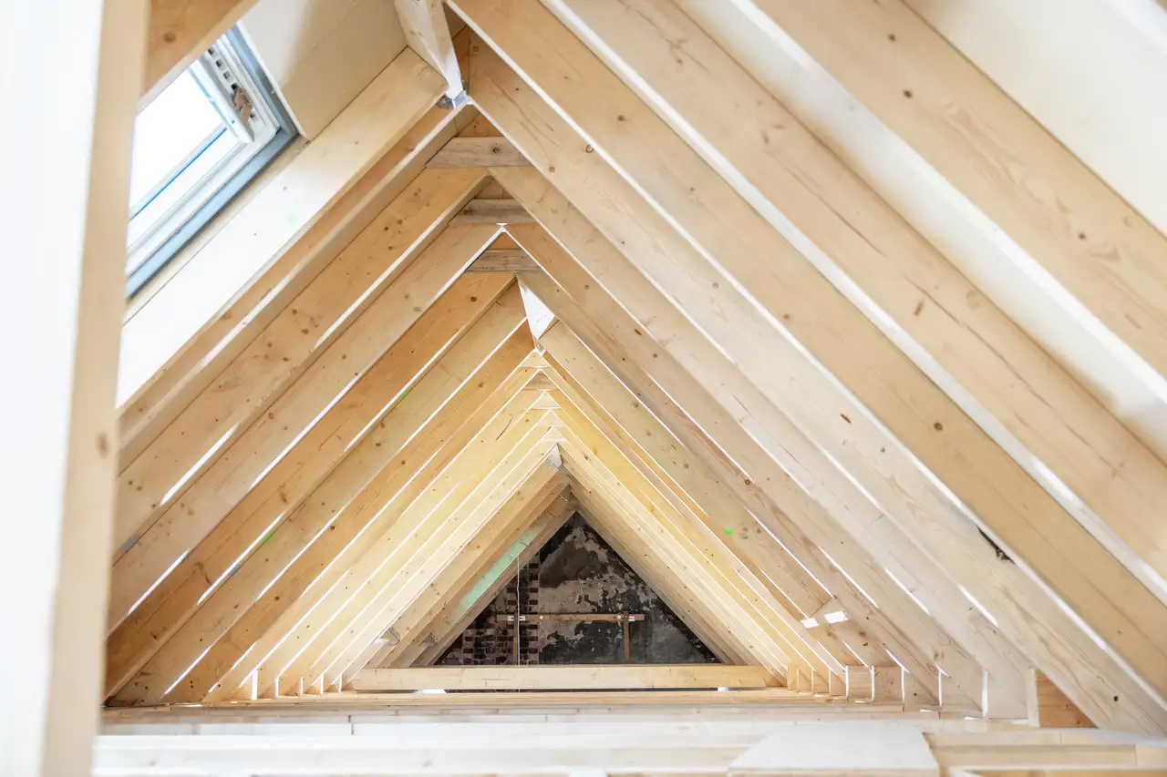 Attic with wooden rafters and an open VELUX roof window.