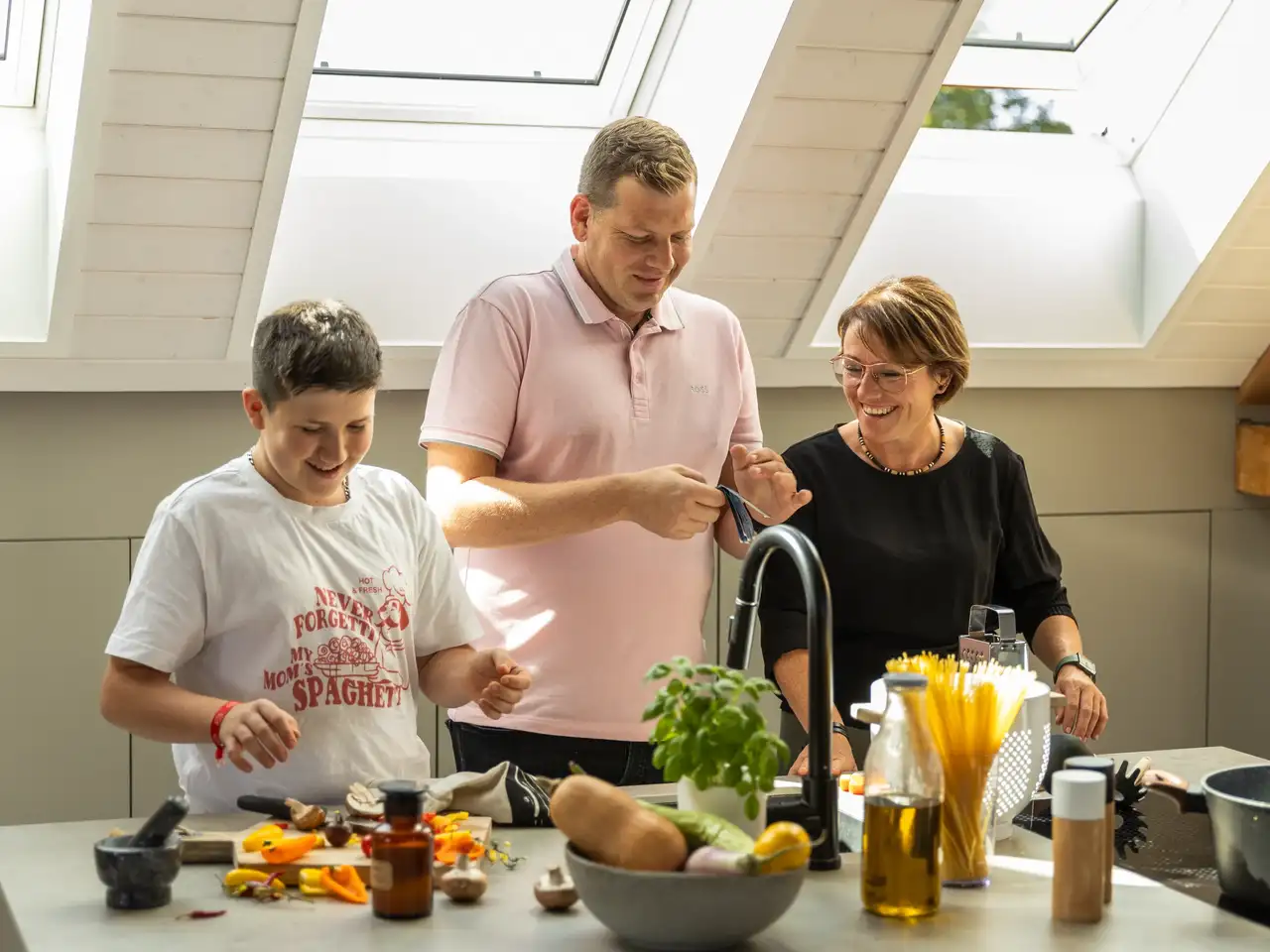 famille dans une cuisine sous les toits avec trois fenêtres de toit VELUX côte à côte