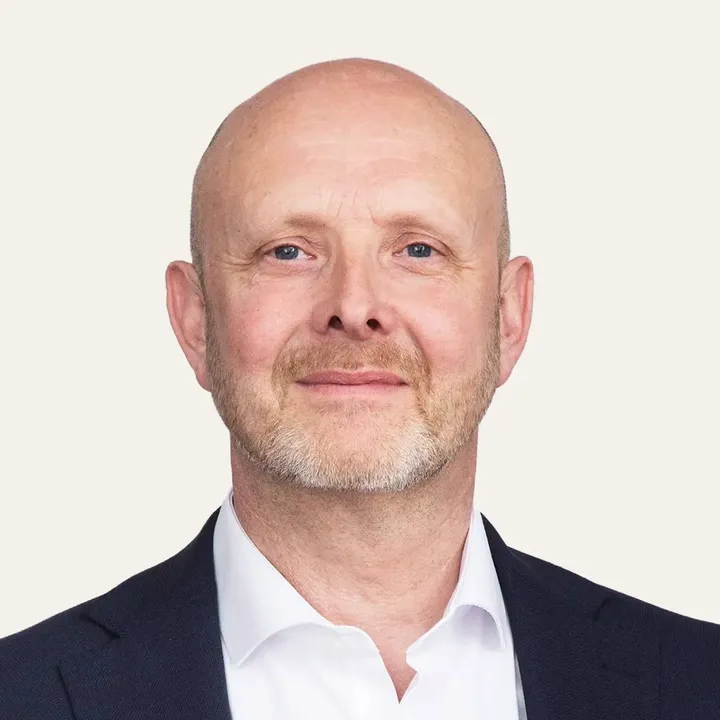 Person in a dark suit and white shirt, professional attire.