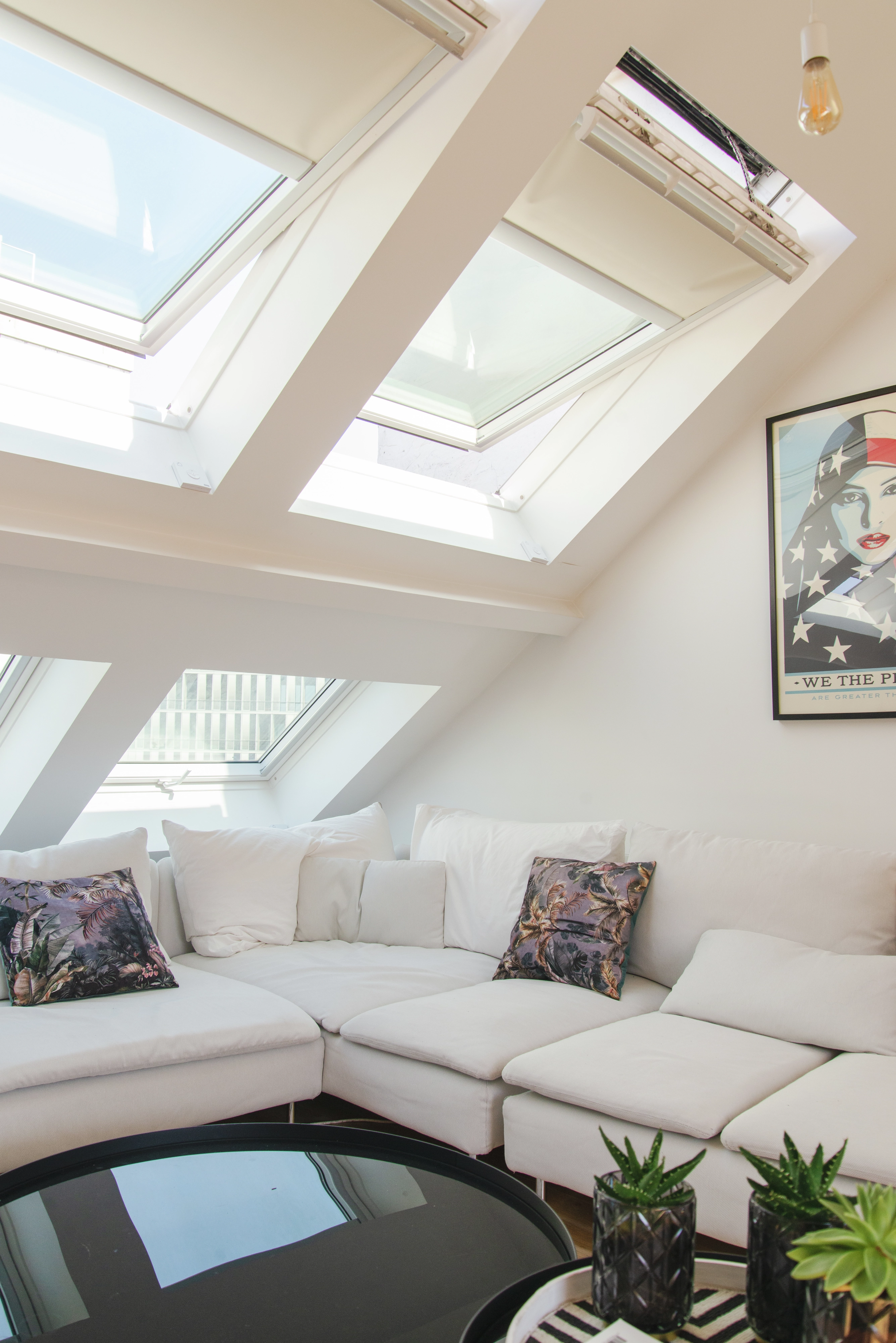 Salon de comble confortable avec fenêtres de toit VELUX, canapé modulable et plantes vertes.