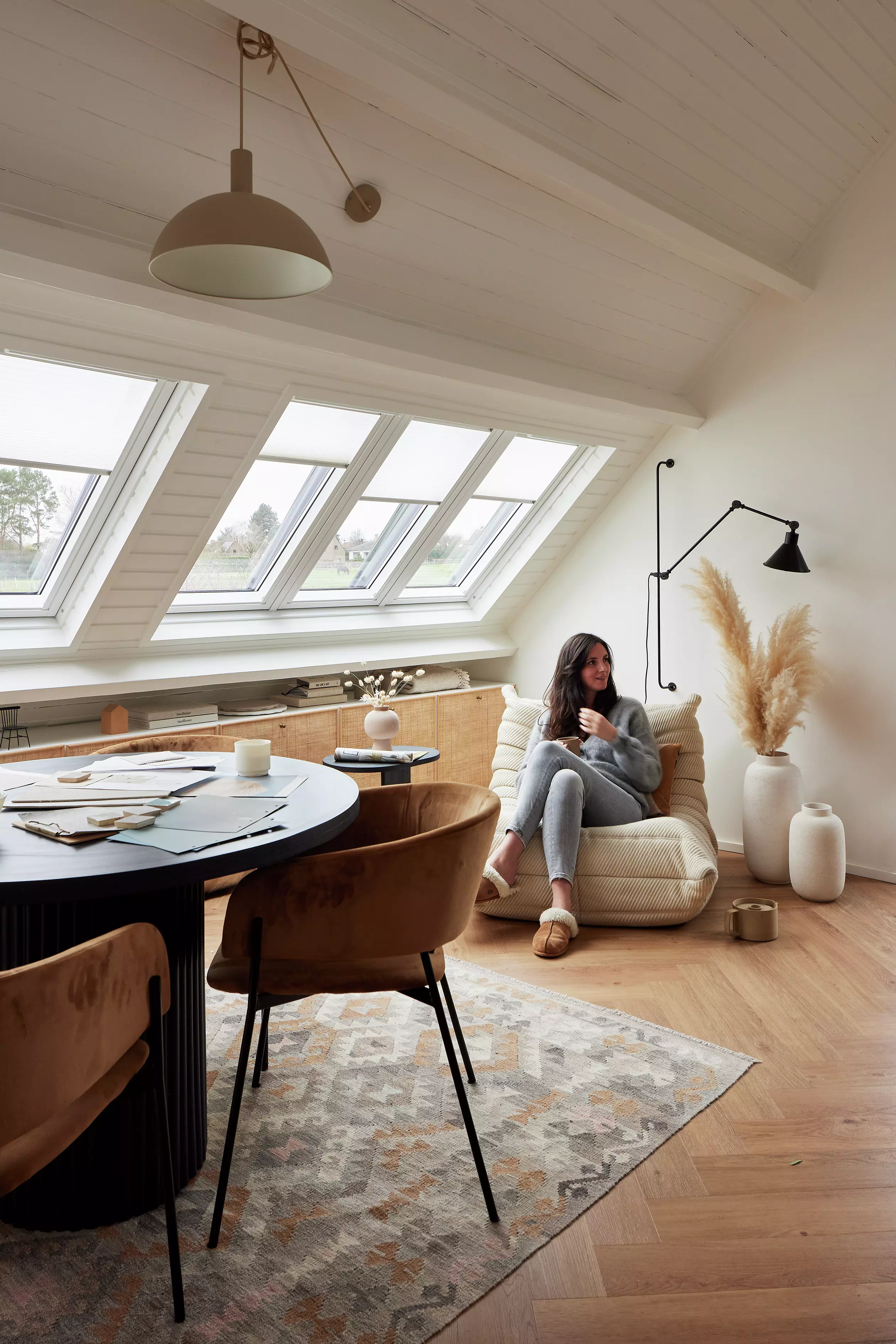 Spazio abitativo luminoso in mansarda con finestre per tetti VELUX, pavimenti in legno e mobili moderni.