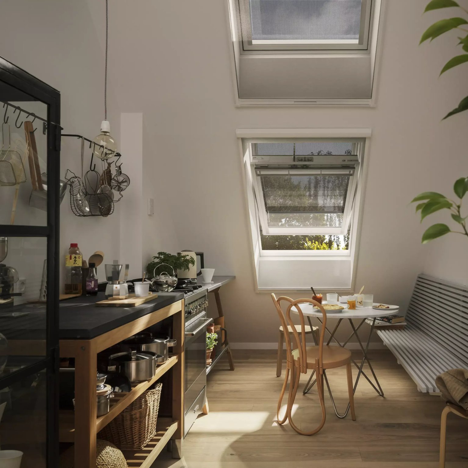 Attic kitchen with sloped ceiling and open VELUX roof windows, natural light entering.