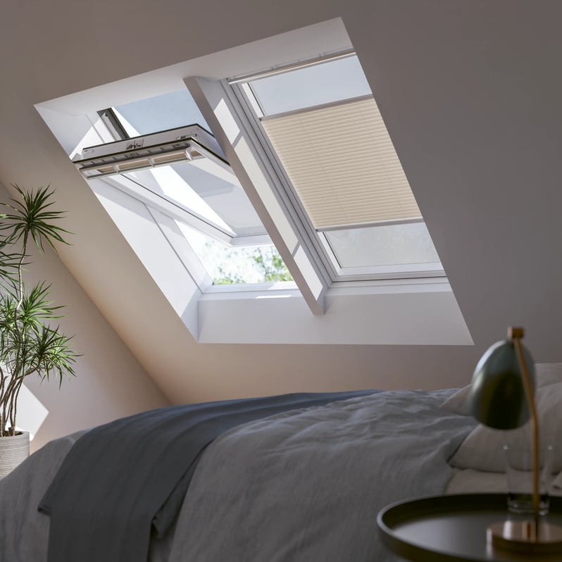 Attic bedroom with sloped ceiling and open VELUX roof window, natural light entering.