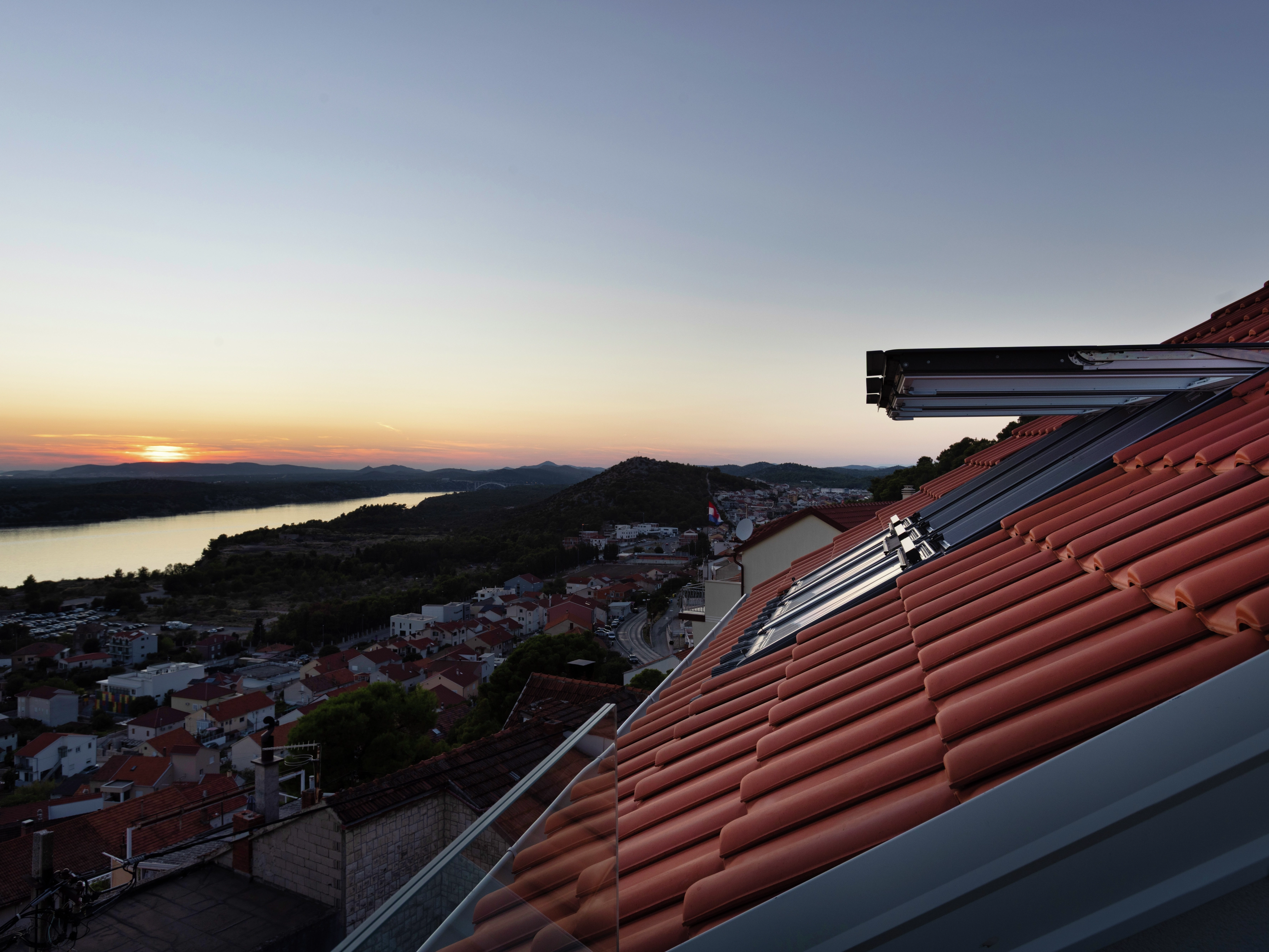 Rooftop view with open VELUX roof windows at sunset.