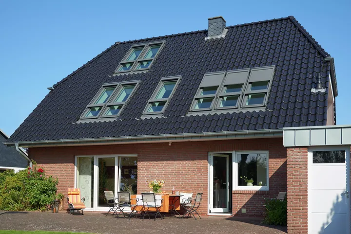 Einfamilienhaus mit Ziegelwänden und VELUX Dachflächenfenstern, Vorgarten und Terrasse.
