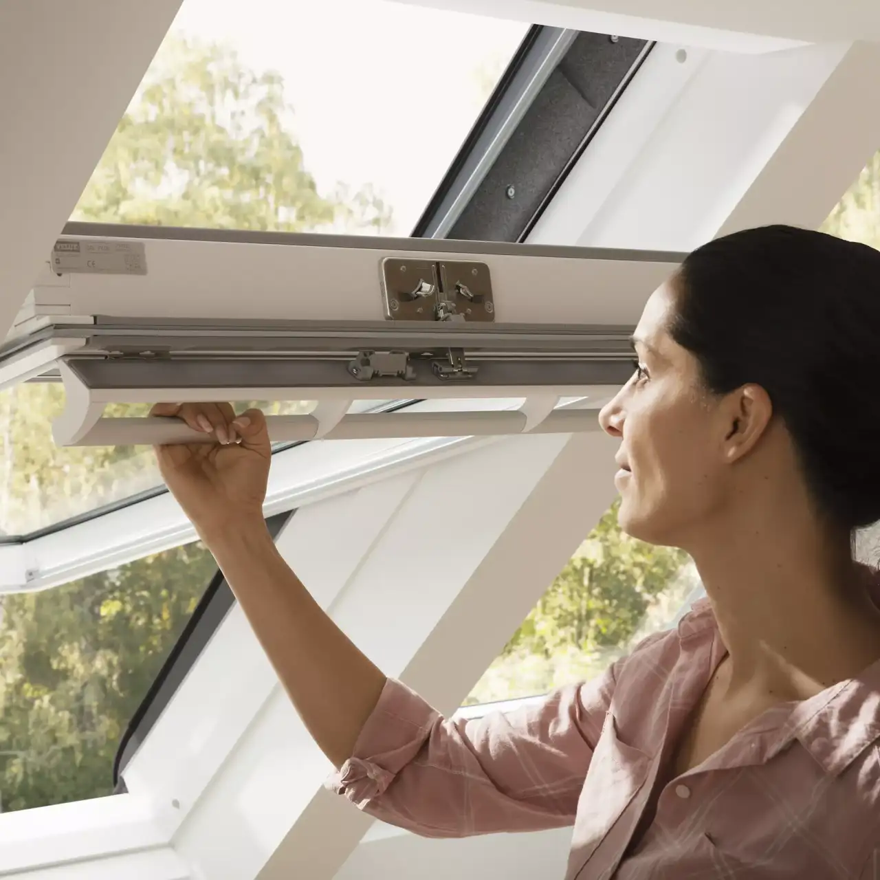 Hände, die ein VELUX Dachflächenfenster einbauen, wodurch der Raum mit natürlichem Licht aufgewertet wird.