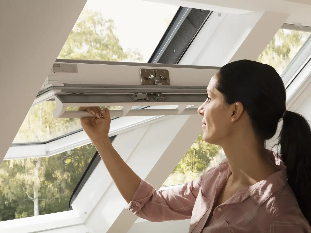 personne ouvrant une fenêtre de toit VELUX dans des combles lumineux
