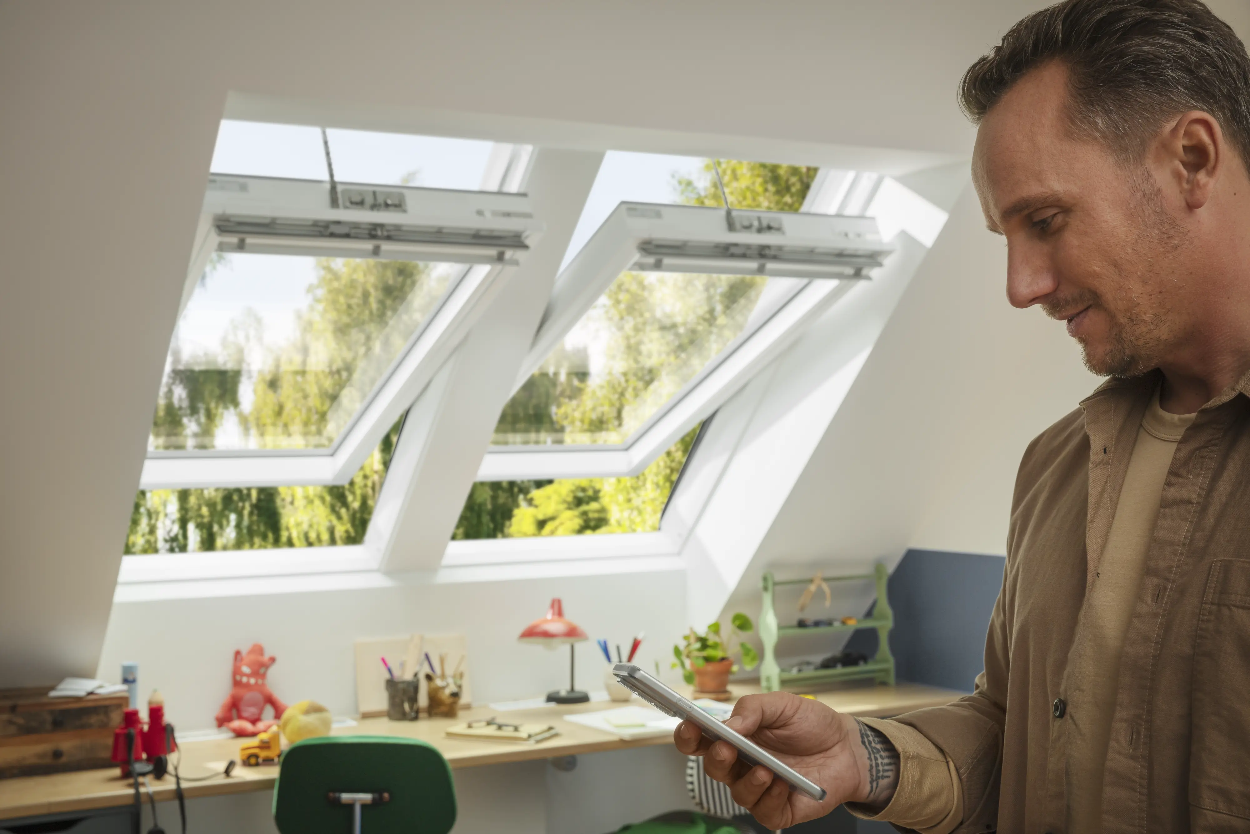 Radni prostor u potkrovlju sa VELUX krovnim prozorima, stolom i zelenom stolicom.