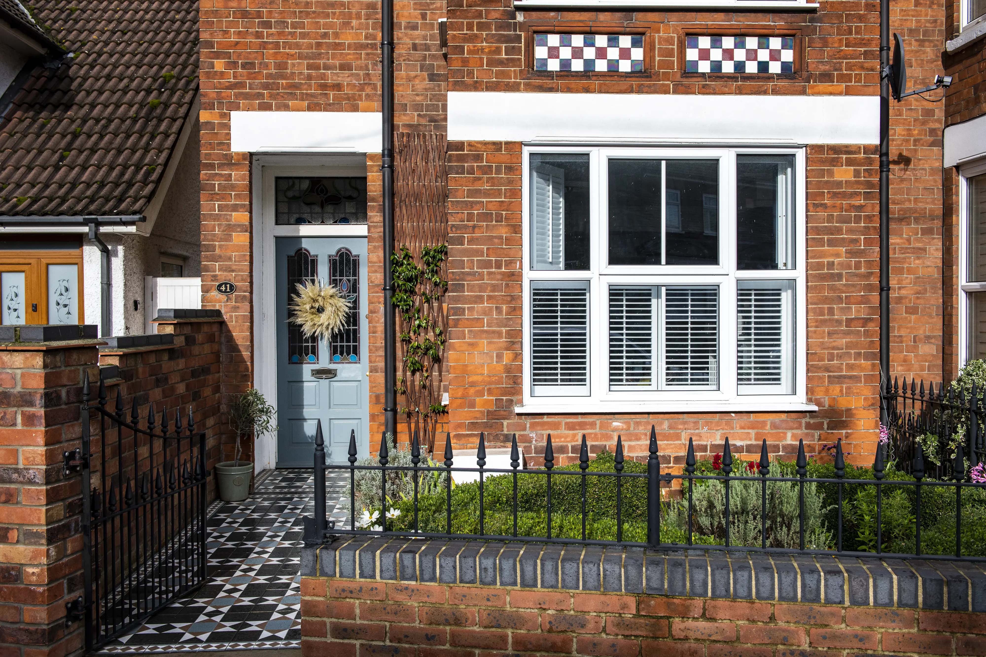 Terraced house entrance with blue door, brick facade, and garden.