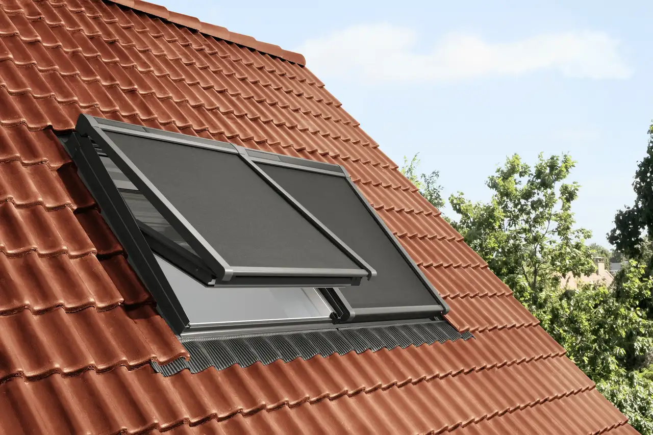 VELUX roof window on a red tiled roof with anti-heat blinds.