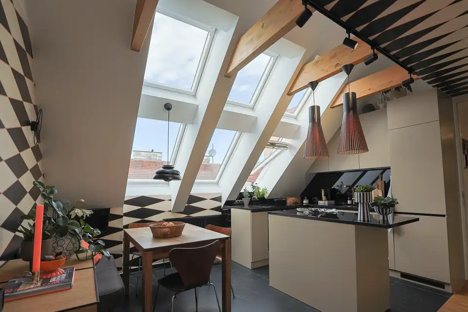 Cucina con zona pranzo adiacente separata da un’isola, illuminata da sei finestre per tetti.