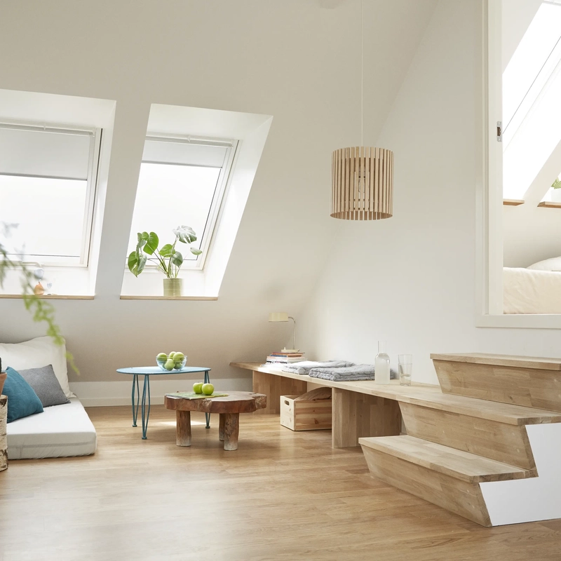Attic living space with sloped ceiling and VELUX roof windows, cozy seating area.