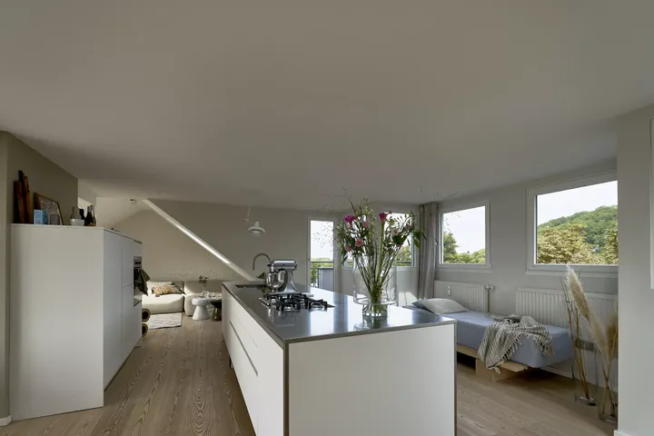 Offener Wohnbereich mit moderner Küche und gemütlicher Lounge-Ecke, durchflutet von natürlichem Licht.