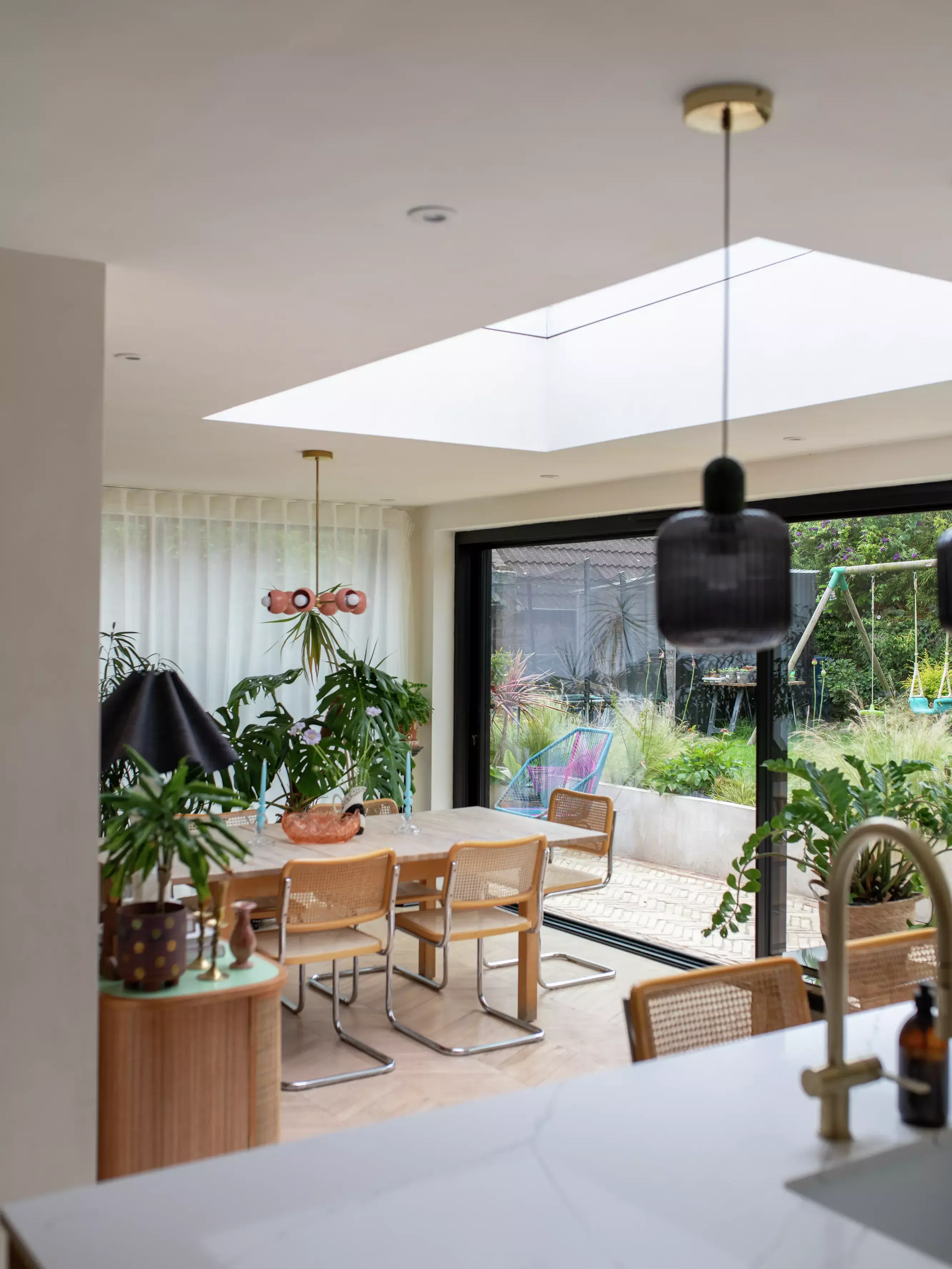 Modern dining room with VELUX skylight overlooking a garden.