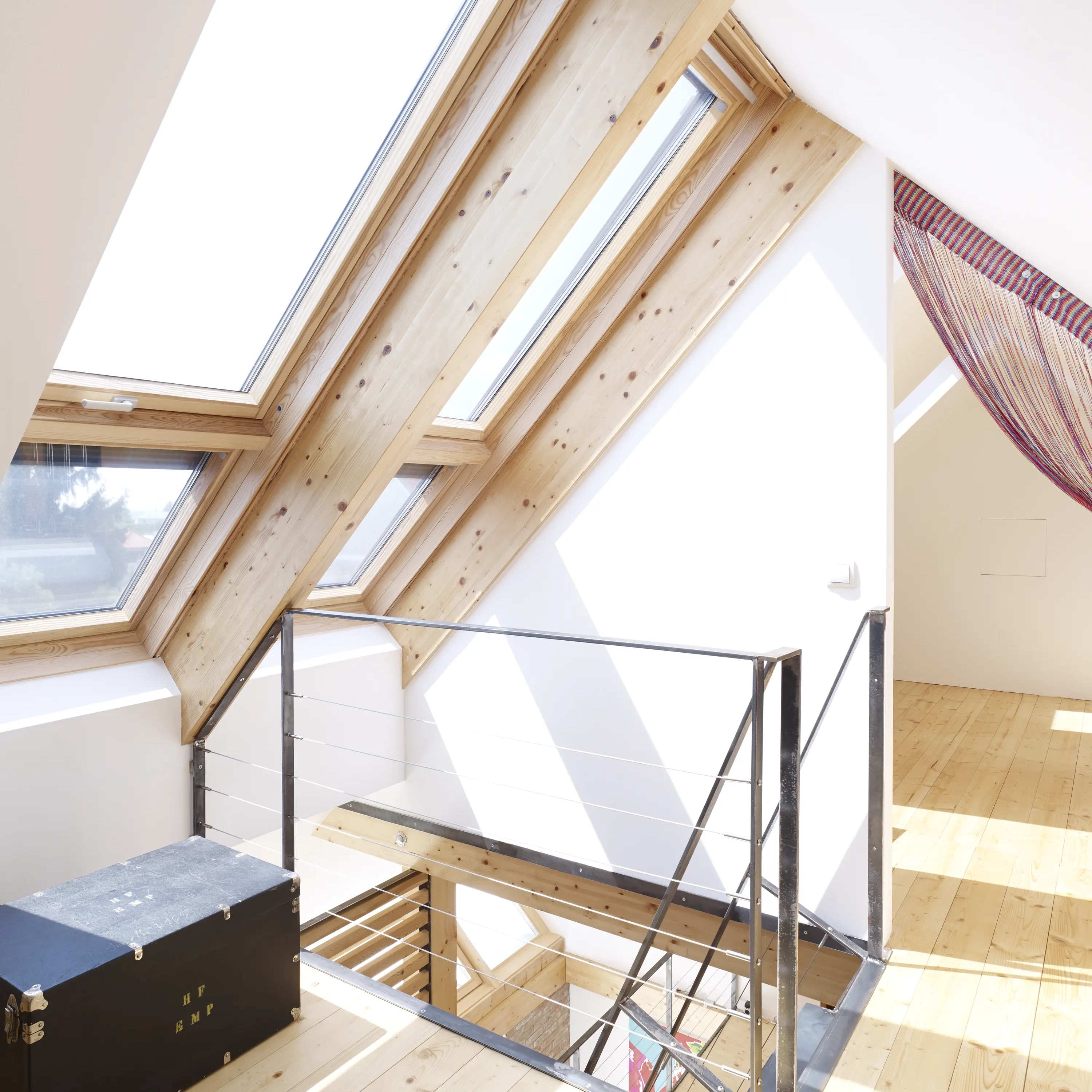 Attic with sloped ceiling and VELUX roof windows, natural light streaming in.