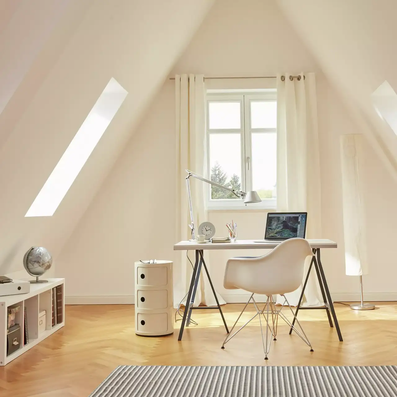 Modernes Homeoffice auf dem Dachboden mit VELUX Dachflächenfenstern und minimalistischen Möbeln.