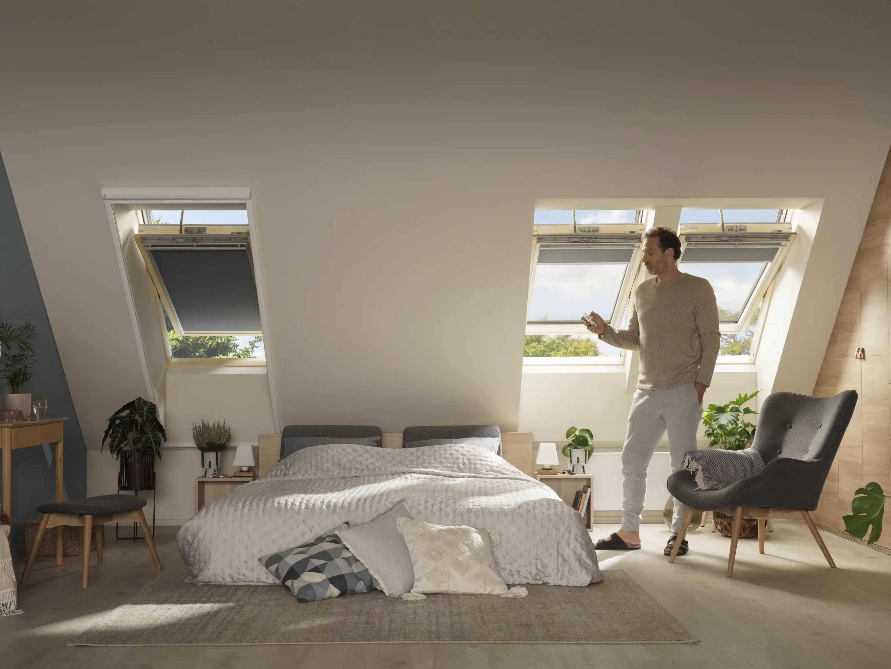 Spavaća soba u potkrovlju sa kosim stropom i otvorenim VELUX krovnim prozorima, moderno uređena.