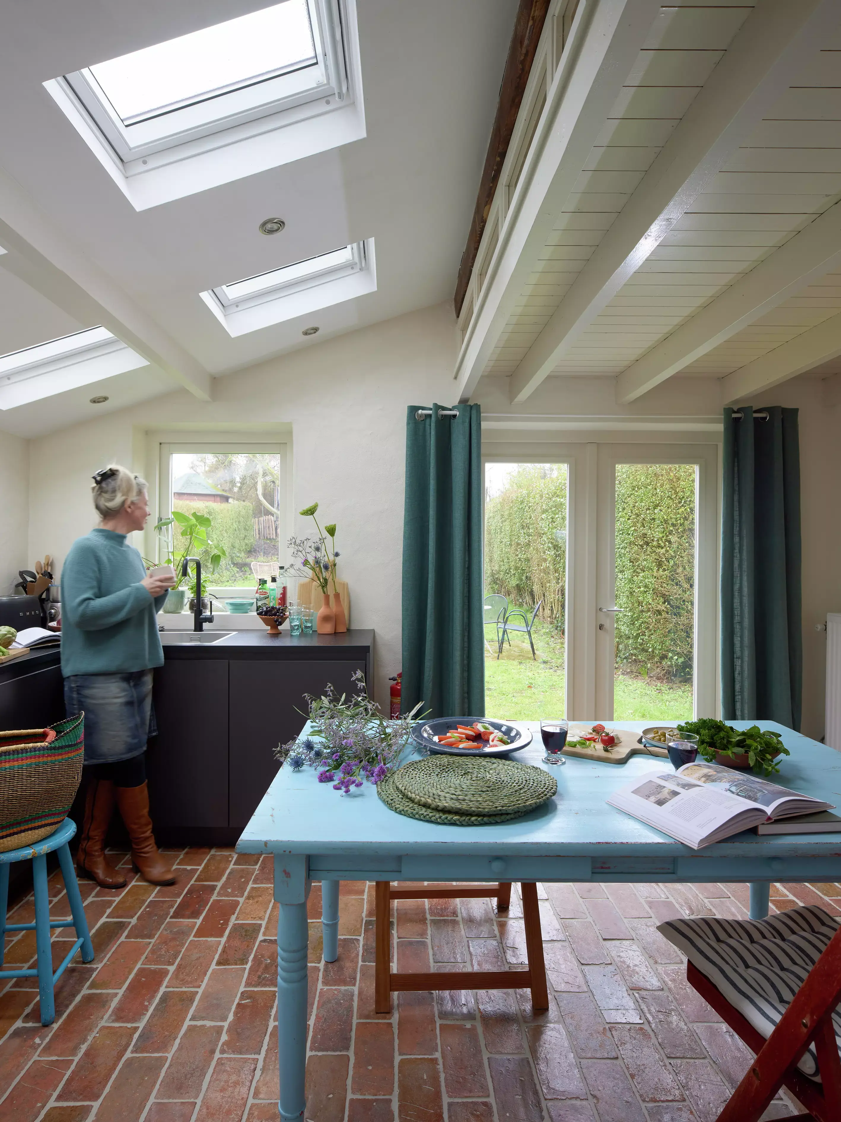 Cuisine confortable avec des carreaux en terre cuite et des fenêtres de toit VELUX donnant sur un jardin.