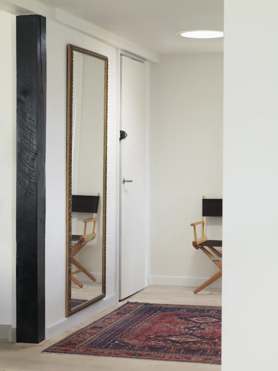 Disimpegno interno con sedia e grande specchio e un tunnel solare VELUX a portare luce naturale