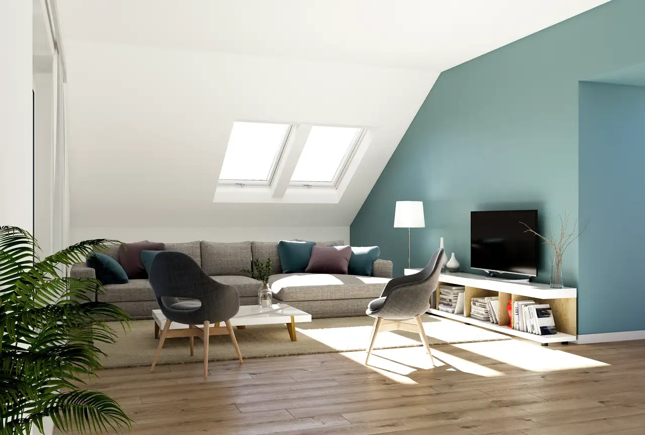 Ampio open space in mansarda con soffitto bianco, due finestre per tetti VELUX e parete verticale verde salvia.