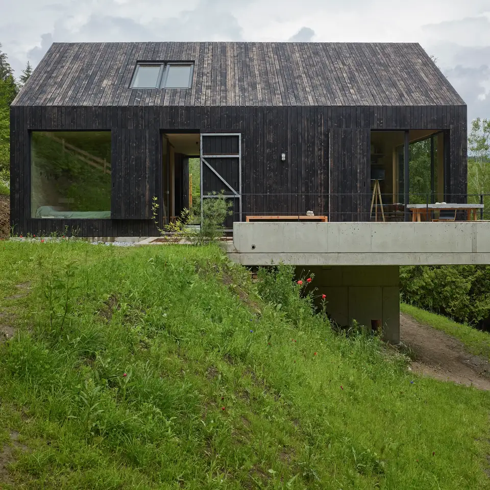 Sommerhus ved sø med mørk træfacade og VELUX Horisontal Duo