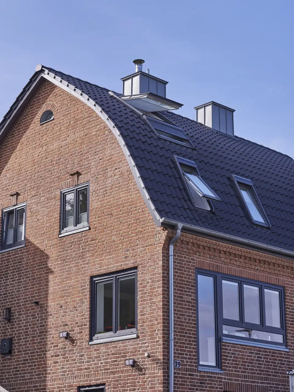Façade ensoleillée d’un bâtiment en briques avec fenêtres de toit modernes VELUX