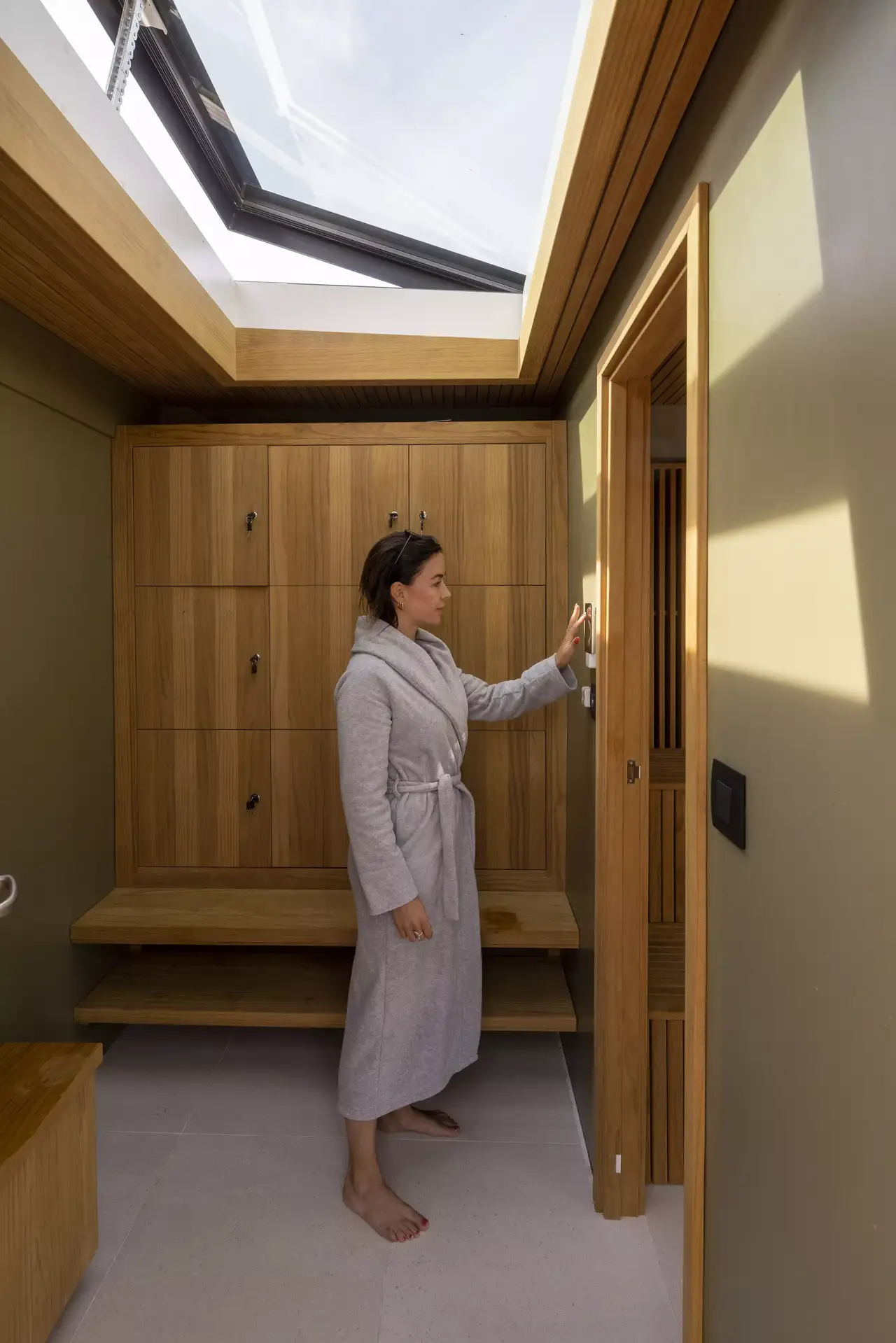 Frau öffnet Sauna vor hölzernen Schließfächern | VELUX Magazin