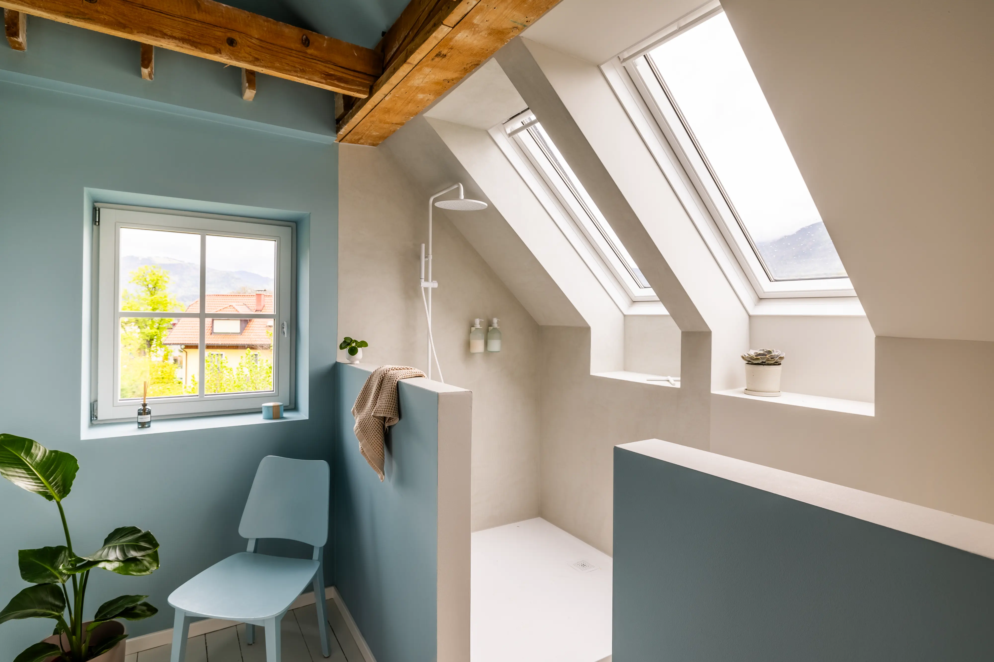 Palėpės vonios kambarys su nuožulniomis lubomis, VELUX stogo langais ir moderniu dušu.