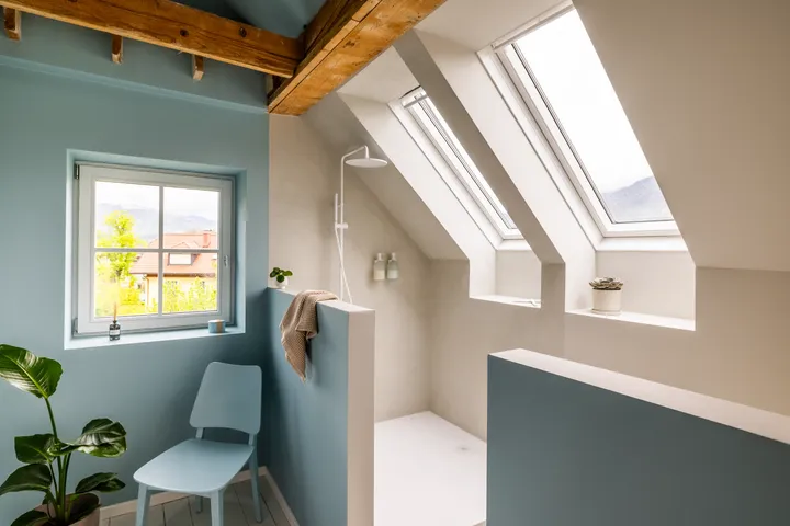 Ümberkujundatud vannituba erksate siniste seinte ja VELUX katuseakendest paistva rohke päevavalgusega, luues naturaalse puiduaktsentidega heleda, avatud ja kutsuva atmosfääri. | VELUX.