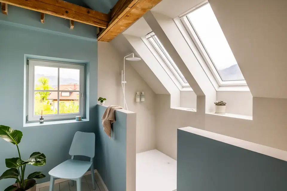 Kupatilo u potkrovlju sa kosim plafonom, VELUX krovnim prozorima i modernim tušem.