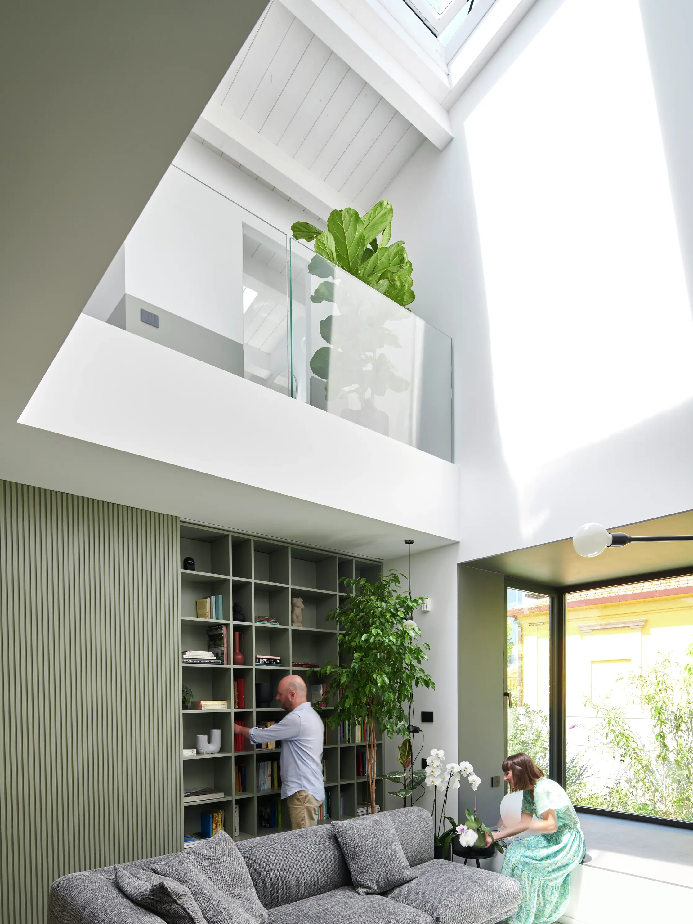Soggiorno moderno con luce naturale proveniente da una finestra per tetti VELUX, libreria e vista sul giardino.