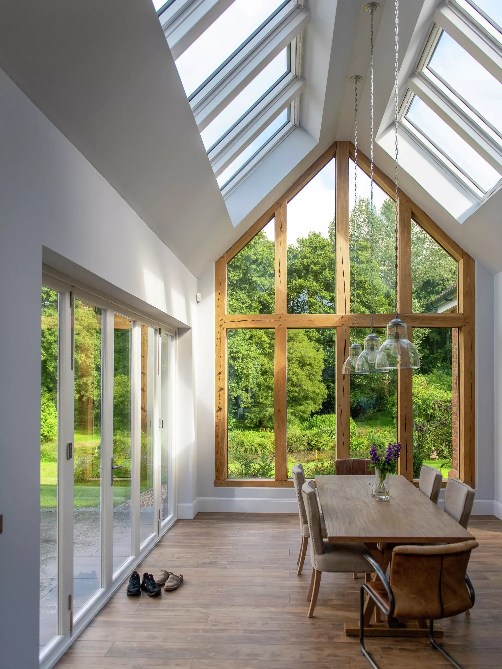 Spacious dining room with VELUX roof windows and garden view through glass doors.