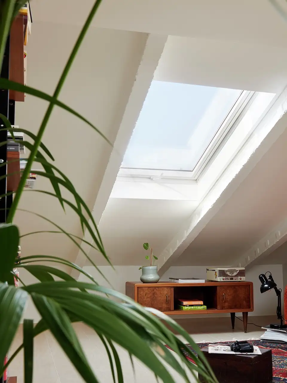 Zolderkamer met schuin plafond, een VELUX dakvenster en vintage decoratie. 