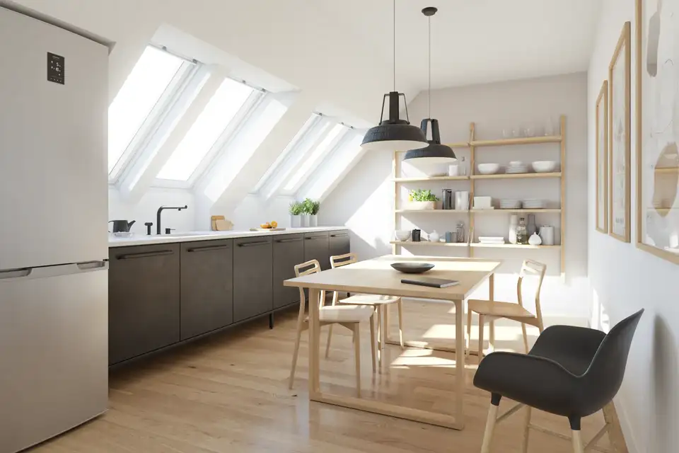 Cucina in mansarda con più finestre per tetti affiancate che illuminano in profondità l’ambiente.