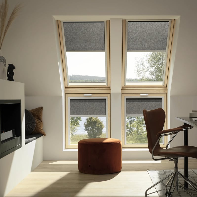 Attic home office with sloped ceiling and VELUX roof windows, modern decor.