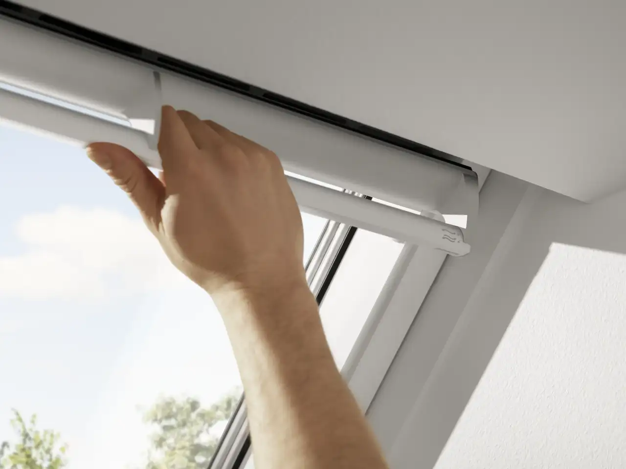 Main actionnant la barre de ventilation d’une fenêtre de toit VELUX en position d’aération.