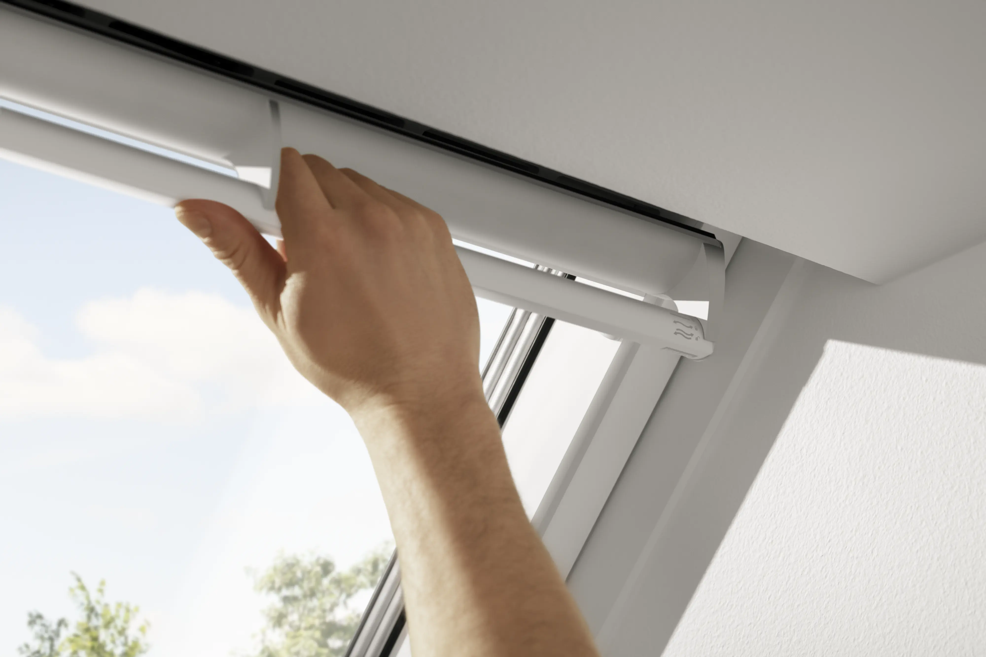Kéz állítja a VELUX tetőablak felső kilincsét, amely a beépített szellőztető használatát segíti a természetes légcsere támogatására. 