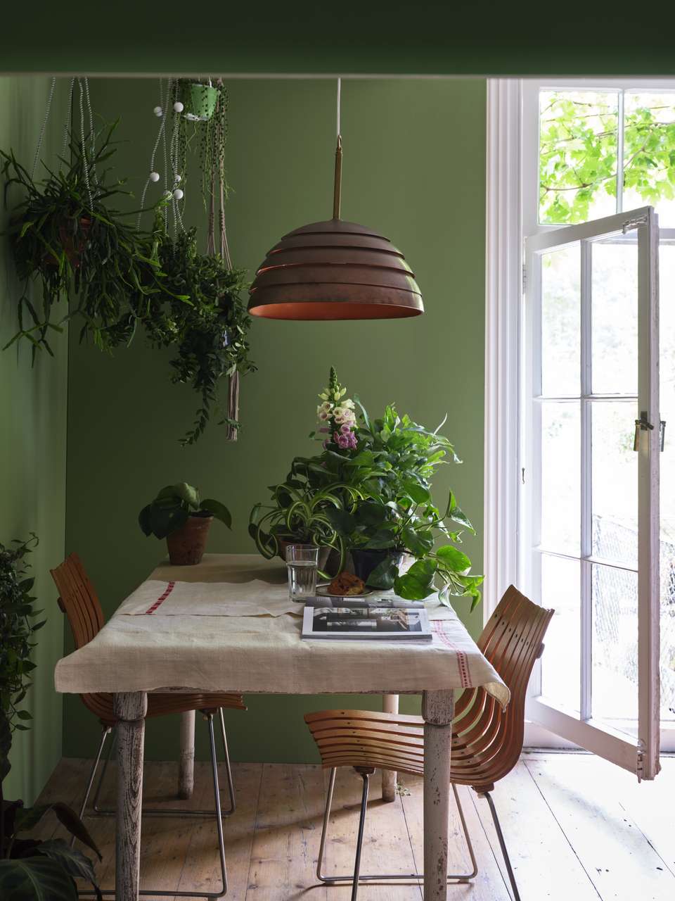 une table à manger et des chaises, où l'accent est mis sur la lumière naturelle et la verdure.