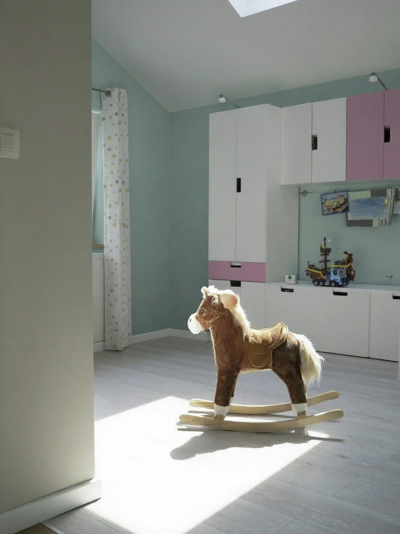 Hobbelpaard in de speelkamer van de uitbreiding, in de zon onder een VELUX dakvenster, voor de opbergkasten van de kinderen